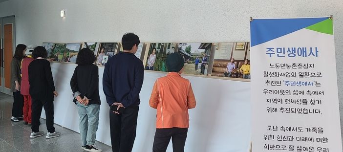 주민들이 전시된 사진을 감상하고 있다
